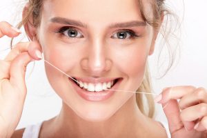 Femme utilisant un fil dentaire