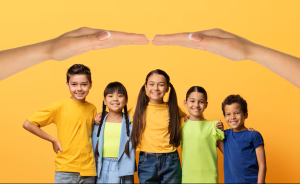 Cinq enfants souriants, de différentes origines, debout côte à côte sur un fond jaune, protégés symboliquement par deux grandes mains au-dessus d’eux.