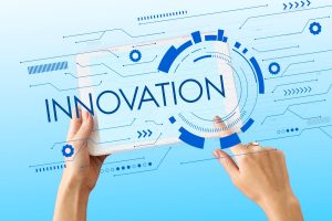 Mains tenant une tablette affichant le mot Innovation, entourée d’éléments graphiques numériques et futuristes sur fond bleu