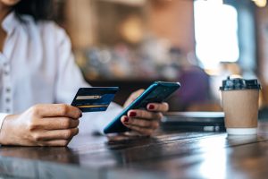 Femme payer par carte de crédit via un smartphone dans un café