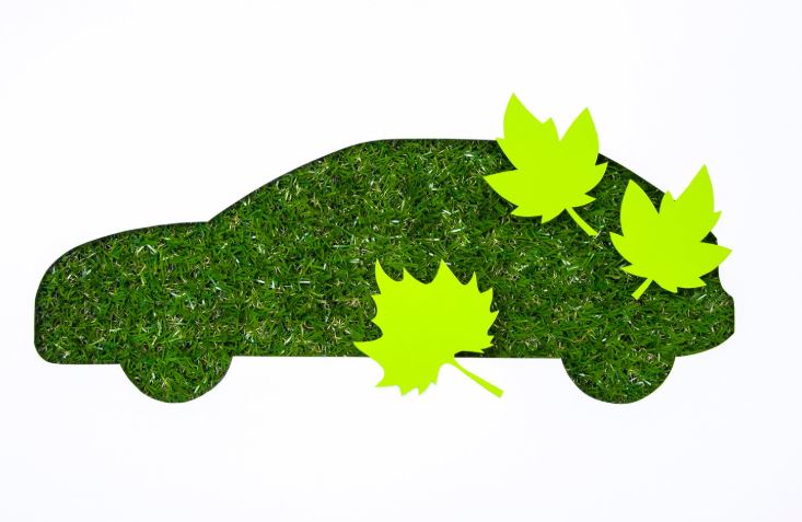 Silhouette d’une voiture faite d’herbe verte avec des feuilles vertes posées dessus, symbolisant une voiture écologique