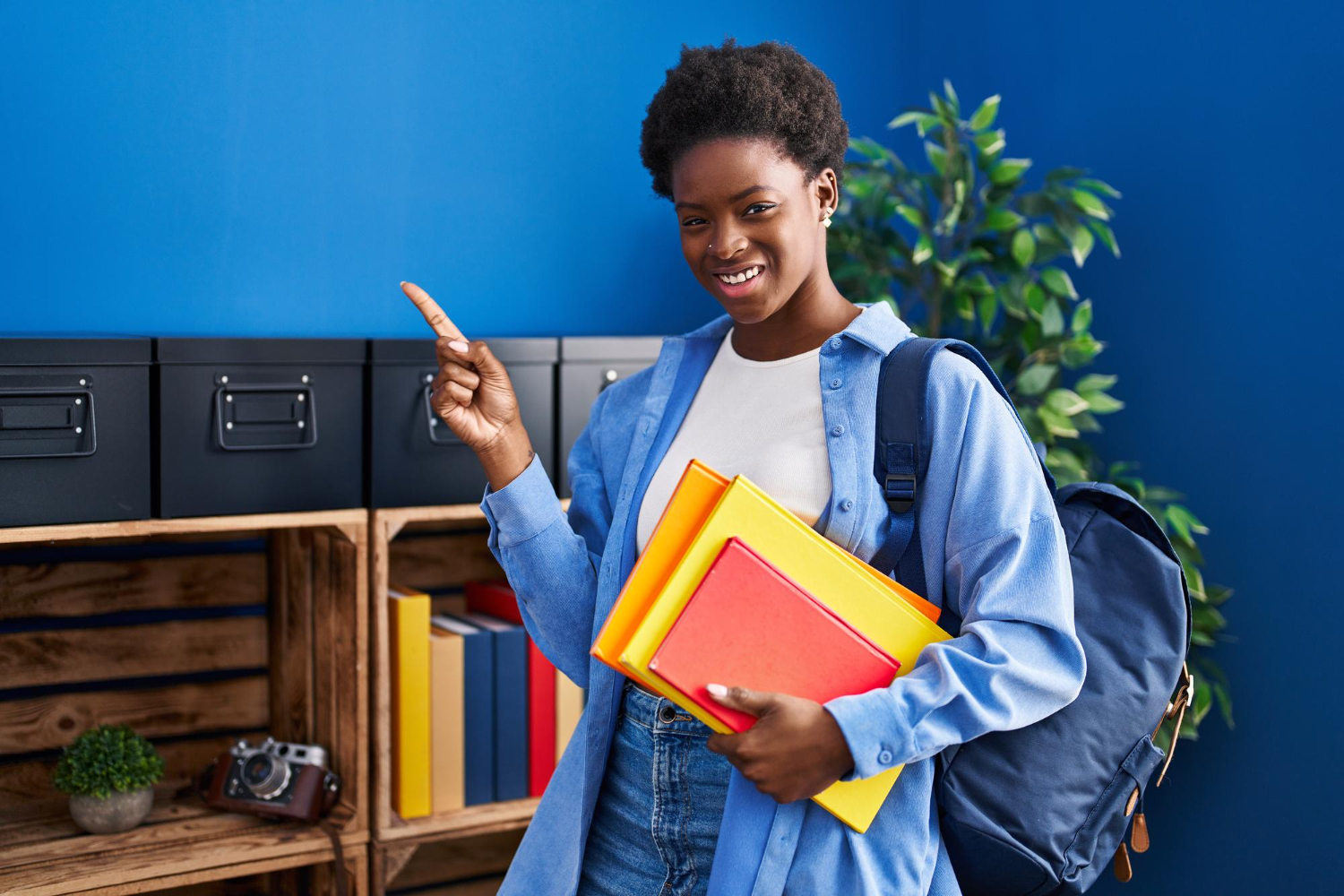 Étudiante souriante avec livres et sac à dos pointant du doigt ou jeune étudiant sur un campus