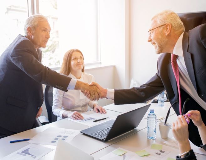 hommes d'affaires se serrent la main par-dessus une table de réunion pour conclure une vente