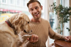 Un homme souriant tient la patte de son chien Golden Retriever