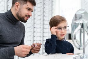 Un enfant essaie des lunettes devant un miroir chez un opticien