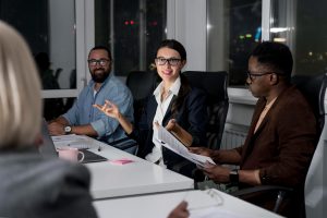 Un groupe diversifié de professionnels participe à une réunion de travail nocturne autour d'une table de bureau