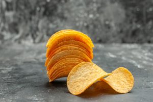 Pile de chips de pommes de terre incurvées et dorées sur un fond gris