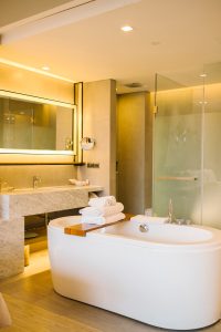 Une salle de bain luxueuse et moderne dotée d'une baignoire îlot élégante avec du linge plié sur un pont de baignoire en bois