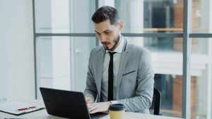 Un professionnel concentré travaillant sur son ordinateur portable dans un bureau moderne.